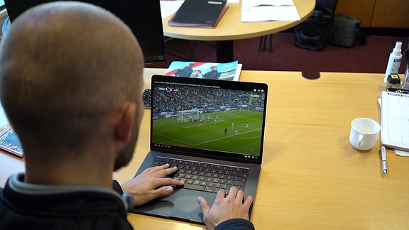 Eine Person schaut auf einem Laptop ein Fußballspiel.