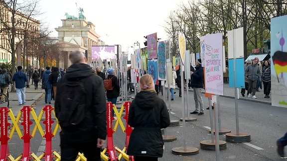 Menschen vor "Mauernachbildung" aus historischen Plakaten