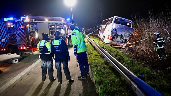 Einsatzkräfte der Feuerwehr und Polizei arbeiten an einer Unfallstelle auf der Autobahn 44 an einem verunfallten Bus