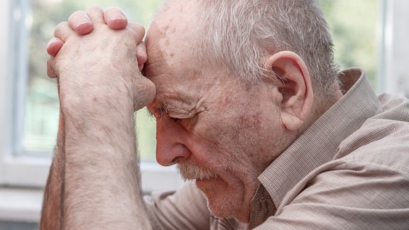 Senior stütz Kopf auf Hände