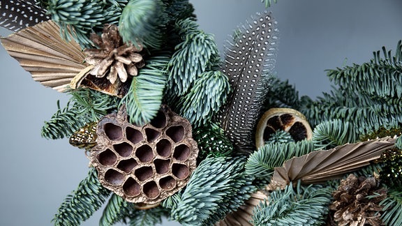 Handgefertigte hölzerne Weihnachtsglocken, Tannenzweige und Tannenzapfen. Weihnachtsdekoration mit Ornamenten und getrockneten Orangenscheiben. 