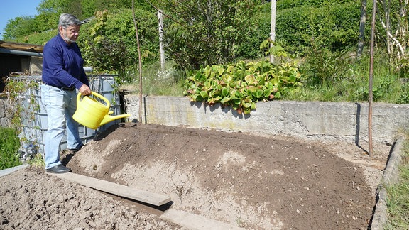 Gartenexperte Klaus Eckardt gießt Hügelbeet 