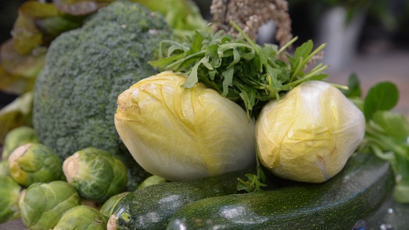 Verschiedene Gemüsesorten auf einem Teller: Zucchini, Chicorée, Rosenkohl, Brokkoli, Rucola