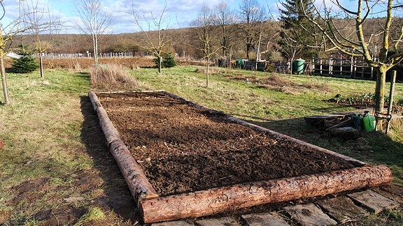 Fertig zur Bepflanzung vorbereitetes Beet mit Umrandung aus Baumstämmen