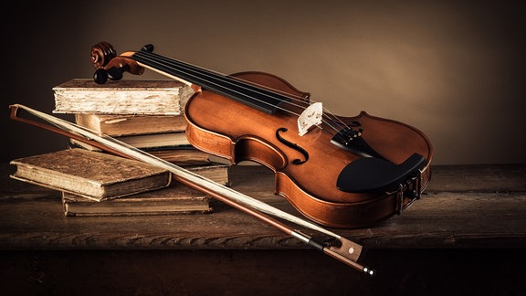 Eine Violine liegt auf Büchern.