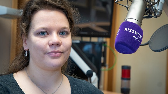 Portrait von Julia Nagel (junge Frau mit langen braunen Haaren sitzt im MDR-Studio neben einem Mikrofon)