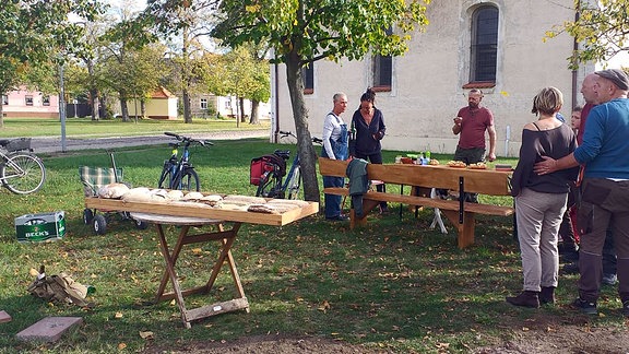 Menschen stehen an einer Essenstafel vor der Kirche in Diebzig