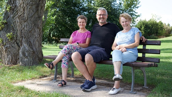 Carola Bär, Marco Trabitz, Sabine Hirsch sitzen gemeinsam auf einer Parkbank