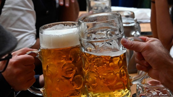 Männer halten Biergläser in der Hand.