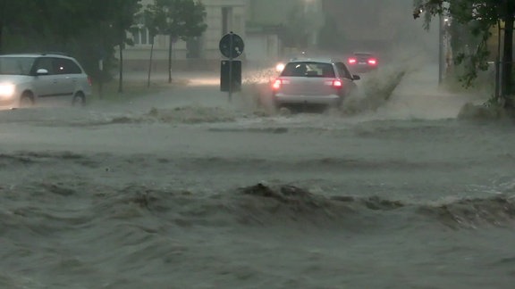 Autos fahrne durch hohes Wasser nach Starkregen.