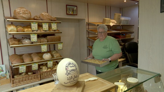 Eine Frau trägt ein Blech in einer Bäckerei.