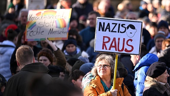 Demonstrantin hält ein Plakat mit Aufschrift 'Nazis raus'