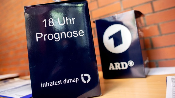 Wahlurnen von Infratest dimap für die Prognose der ARD um 18 Uhr stehen auf einem Tisch.