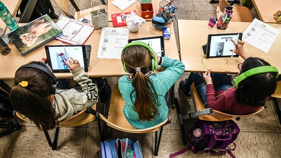 Kinder arbeiten im Unterricht auf ihren Tablets.