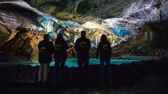 Personen stehen in der Baumannshöhle, die bläulich erleuchtet ist