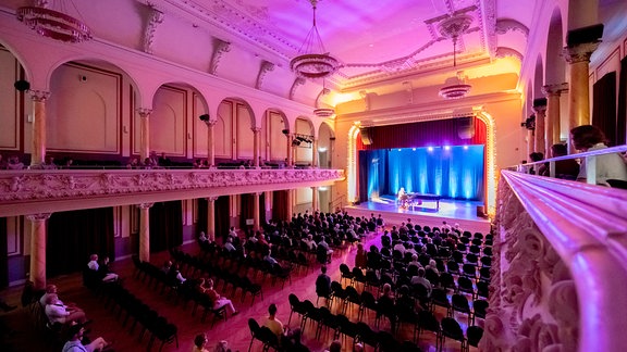 Blick durch den Saal auf die Bühne des Schützenhauses in Pößneck beim Auftritt von Bodo Wartke im MDR-Musiksommer.