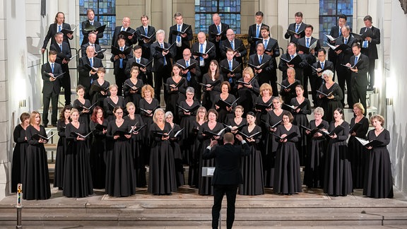 Im Altarraum der Stadtkirche St. Maximi in Merseburg stehen die Sängerinnen und Sänger des MDR-Rundfunkchors. Am 18. Juni fand dort eines der drei Eröffnungskonzerte des MDR-Musiksommers 2022 statt. Dirigent Philipp Ahmann hatte neben Werken von Schubert und Wolf auch eine Uraufführung eines Werkes von Komponist Michael Langemann auf das Programm gesetzt.