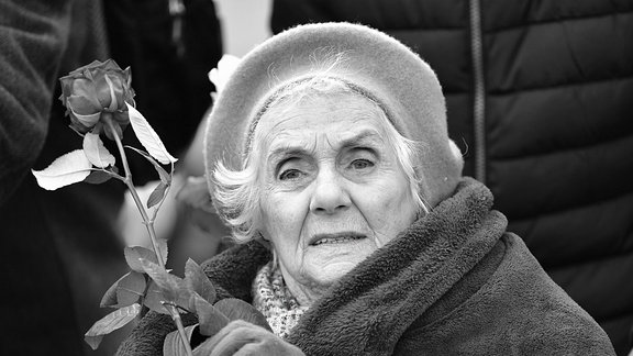 Die Buchenwald-Überlebende Eva Fahidi-Pusztai hält bei einer Gedenkveranstaltung zum 74. Jahrestag der Befreiung des früheren KZ Buchenwald auf dem ehemaligen Appellplatz eine Rose in der Hand.