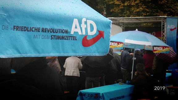 Ein Sonnenschirm mit AfD Logo und dem Schriftzug "Die 'Friedliche Revolution' mit dem Stimmzettel"