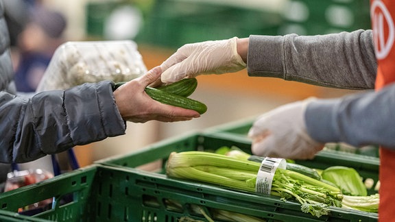 Ein Verkäufer übergibt Gurken an eine ältere Frau