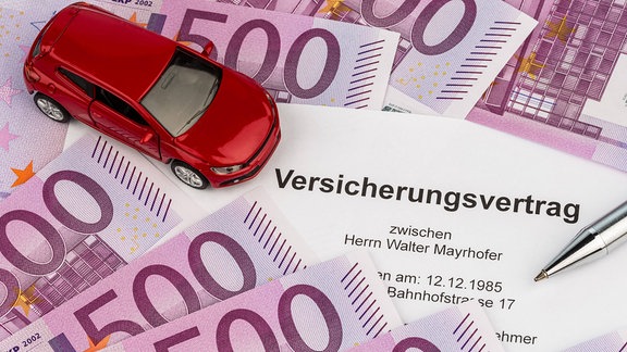 Spielzeugauto auf Geldscheinen und Versicherungsvertrag