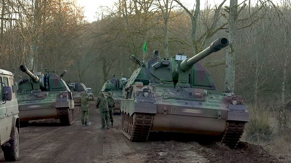 Soldaten neben Panzern in einem Waldstück