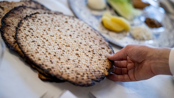 Eine Person legt zu Pessach im Chabad Jüdisches Bildungszentrum Matzen auf den Tisch.