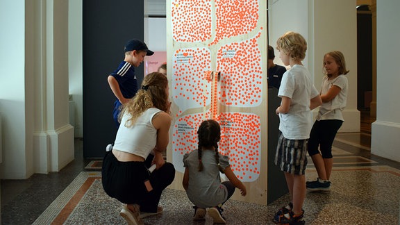 Lehrerin und Kinder an einem Mitmachobjekt im Museum