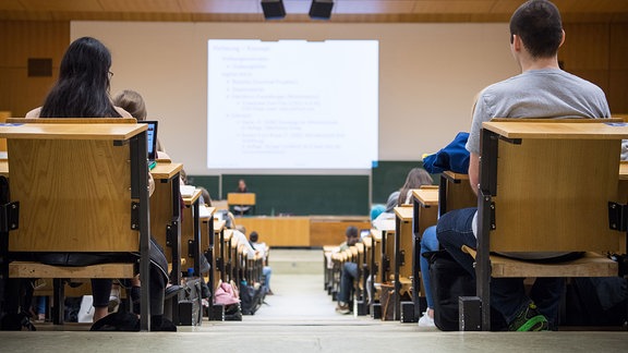 Studentinnen und Studenten sitzen während einer Vorlesung in einem Hörsaal.