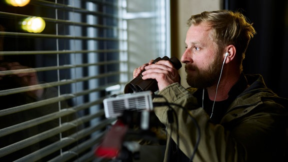 Ein Mann mit Fernglas am Fenster