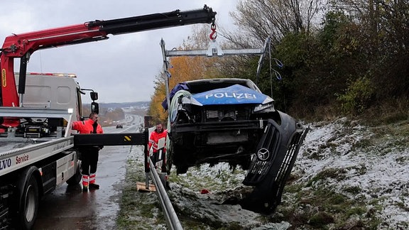 Ein verunglücktes Polizeiauto wird von einem Kran aus dem Straßengraben gehoben