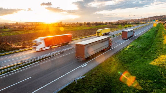 Lkw fahren über eine Straße im Sonnenuntergang.