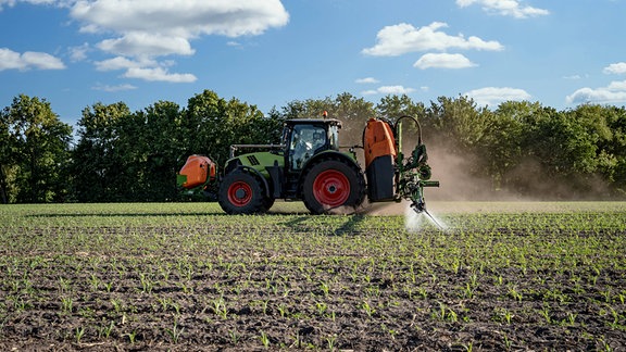 Moderner Traktor mit Feldspritze auf einem Maisfeld im Einsatz