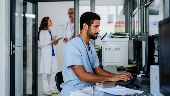 Ein Doktor sitzt an einem Computer.