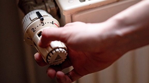 Eine Person benutzt einen alten Heizkörper in einer Berliner Altbauwohnung. 