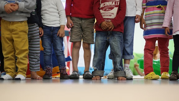 Kinder stehen in einem Kindergarten.