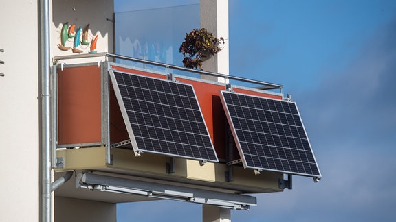 Solarmodule für ein sogenanntes Balkonkraftwerk hängen an einem Balkon.