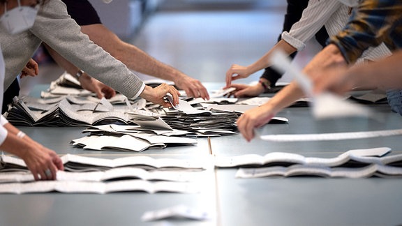 Wahlhelfer und Wahlhelferinnen zählen in einem Wahllokal Stimmzettel für die Bundestagswahl