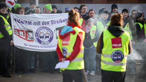 Mitarbeiter der Halleschen Verkehrs-AG (HAVAG) sowie Vertreter von Verdi und Fridays for Future stehen während eines Warnstreiks vor einem Betriebshof. 