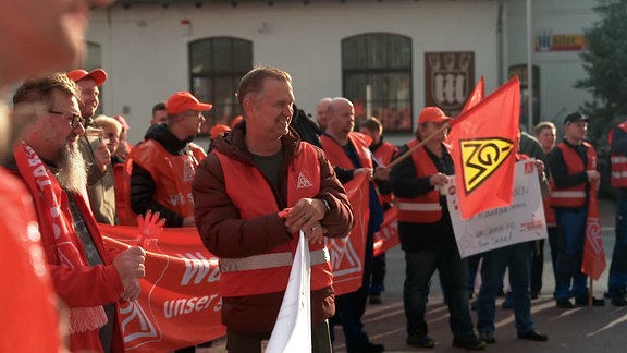 Streikende in Halle mit Warnwesten und Flaggen und Plakate