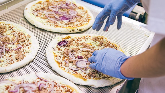 Tunfisch-Tiefkühlpizzen werden in einer Fabrik belegt.