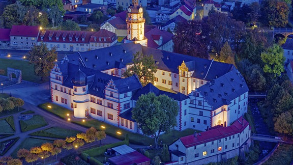 Schloss Ehrenstein mit Schlossgarten in der Abenddämmerung beleuchtet.