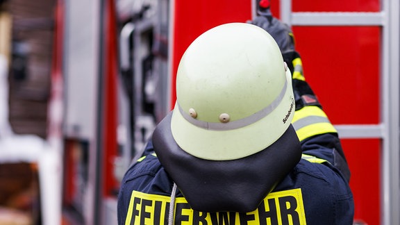 Ein Feuerwehrmann hantiert an einem Einsatzwagen.