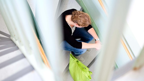 Eine junge Frau posiert am 28.08.2013 auf einer Treppe im Frauenhaus in Nienburg (Niedersachsen).