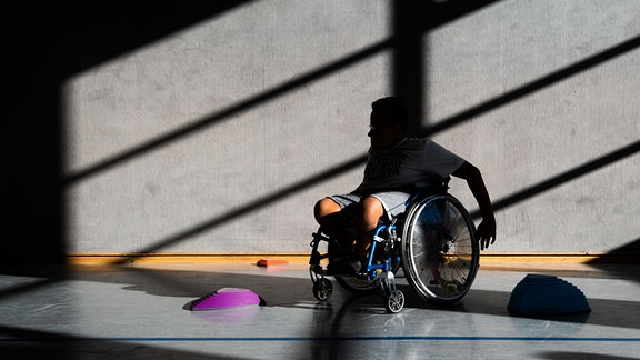 Ein Schüler  fährt mit seinem Rollstuhl Slalom um Hindernisse