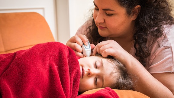 Eine Mutter misst 2022 bei ihrer kleinen Tochter Fieber.