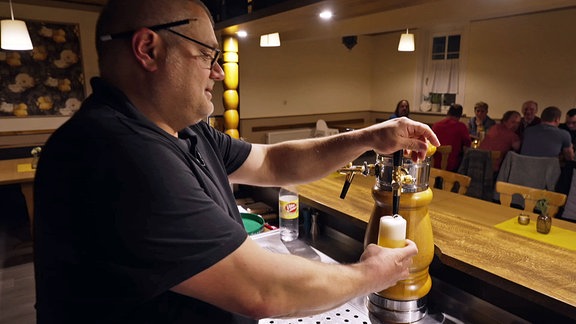 Ein Gastwirt zapft ein Bier.