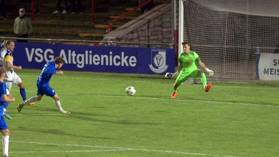 Spieler des VSG Altglienicke spielt den Ball und überwindet den Jenaer Torwart.