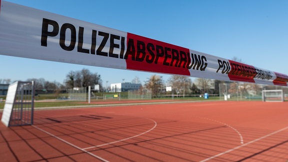 Ein Fußballplatz im Ostragehege ist zur Eindämmung des Coronavirus mit Absperrband der Polizei gesperrt.