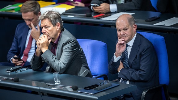 Olaf Scholz verfolgt eine Debatteim Bundestag neben Robert Habeck und Christian Lindner 